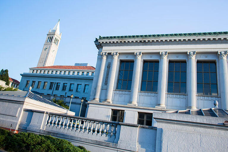 Person walking in front of Doe Library near UC Berkeley Campanile clock tower