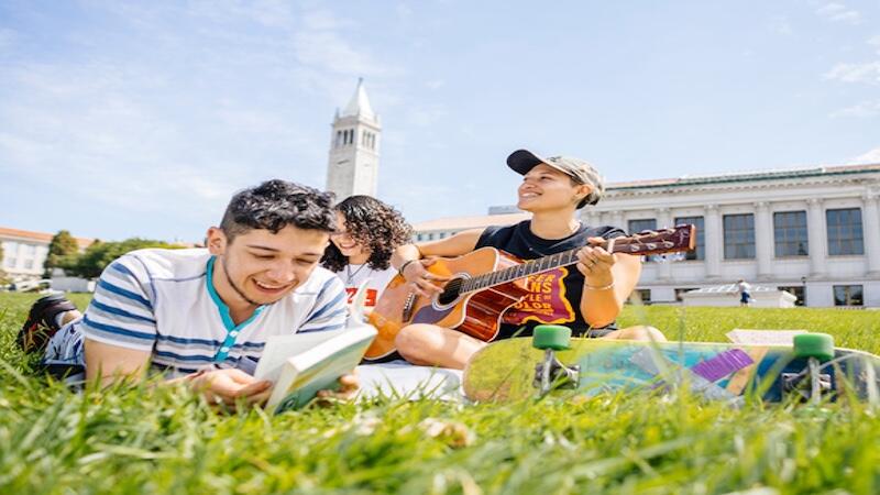 Students hanging on grass and playing guitar