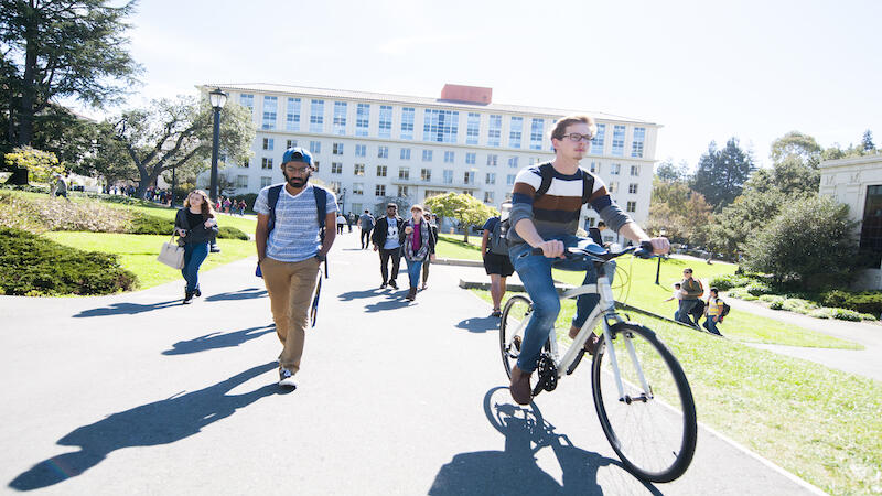Student walking and student riding a bike on UC Berkeley campus